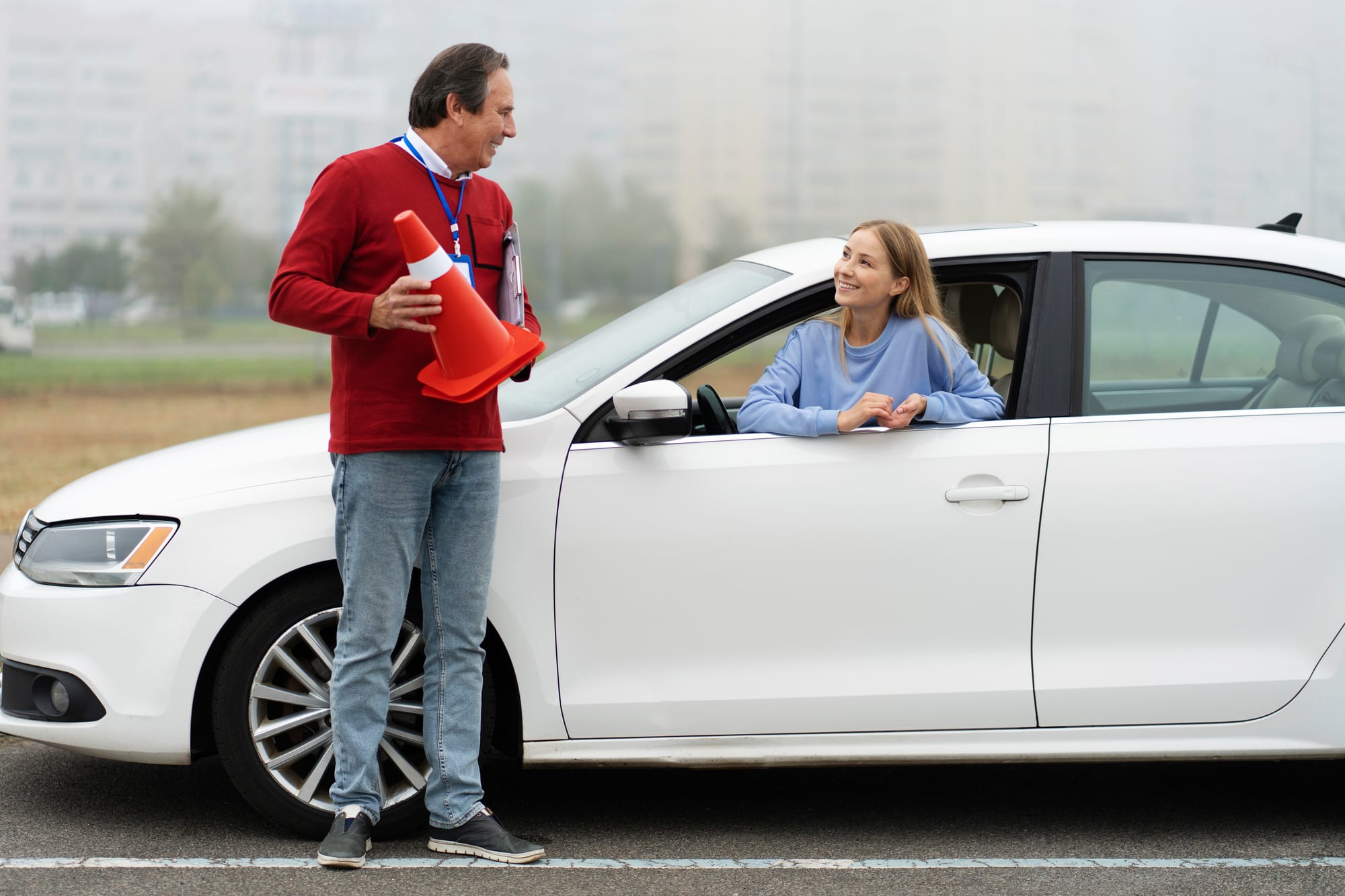 Moniteur et élève à côté d’une voiture, plots d’exercice à la main